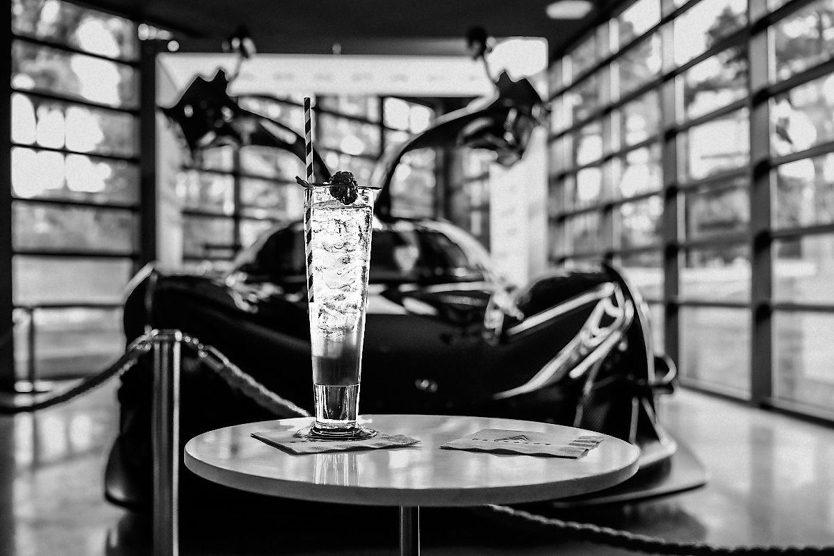 black and white image of cocktail in front of fancy car